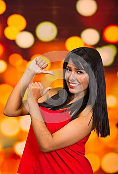 Brunette model posing happily in front of blurry lights background, interacting using hands photo