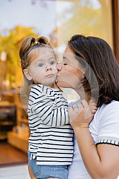 brunette mother kissing baby girl in