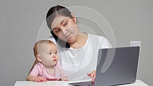 Brunette mother talks with colleague on phone holding baby