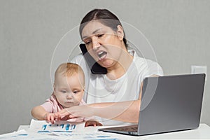 Brunette mother talks with colleague on phone holding baby