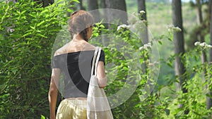 Brunette in open shoulders top walks along green meadow