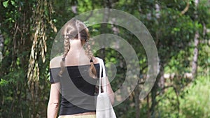 Brunette in open shoulders top walks along green meadow