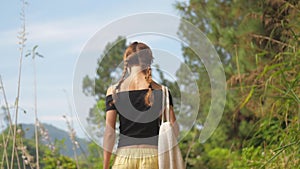 Brunette in open shoulders top walks along green meadow