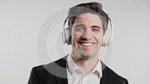 Brunette positive buisnessman listening music with headphones, white studio
