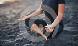 Brunette practicing yoga and meditation in lotus position on the background of the sunset and sea