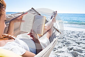 Brunette reading a book while relaxing in the hammock