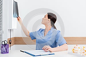 brunette rehabilitologist looking at x-ray