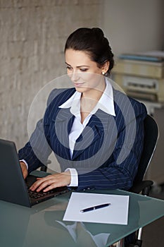Brunette secretary typing letter on laptop