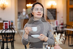 Brunette sitting in cozy cafe with cup of coffee