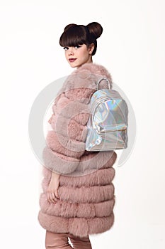 Brunette smiling teen girl in pink fur coat advertise backpack,