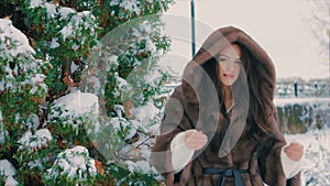 Brunette stylish girl near Snow covered trees in winter, in brown fur coat slow motion