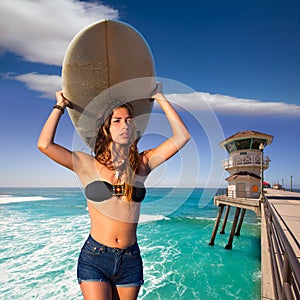 Brunette surfer teen girl holding surfboard in a beach