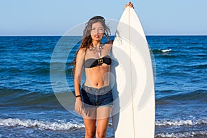 Brunette surfer teen girl holding surfboard in a beach