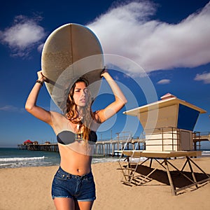 Brunette surfer teen girl holding surfboard in a beach