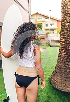 Brunette surfer woman with top and bikini holding surfboard