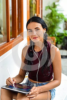 Brunette ukrainian woman artist and illustration drawing, using electronical tablet and stylus, by using touchscreen