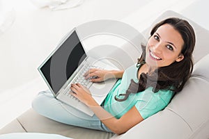 Brunette using her laptop on sofa