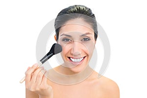 Brunette using a powder brush and smiling