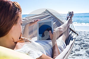 Brunette using tablet while relaxing in the hammock