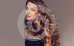 Brunette with voluminous, shiny and curly hairstyle.