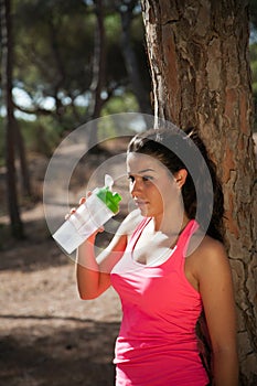 Brunette with water container after sports