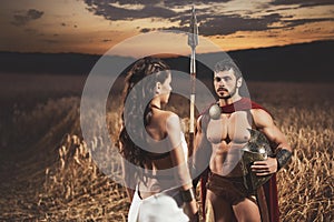 Brunette wearing like greece and man warrior like spartan.