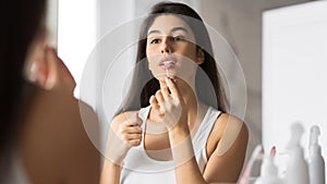 Brunette Woman Applying Lipstick In Front Of Mirror In Bathroom