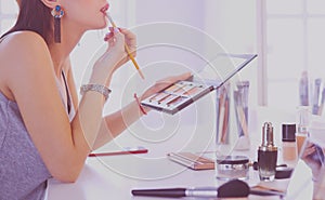 Brunette woman applying make up for a evening date in front of a mirror