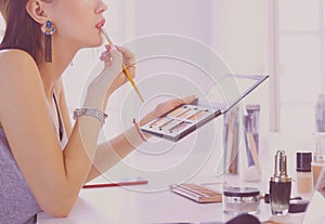 Brunette woman applying make up for a evening date in front of a mirror