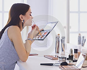 Brunette woman applying make up for a evening date in front of a mirror