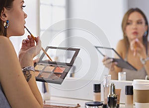 Brunette woman applying make up for a evening date in front of a mirror