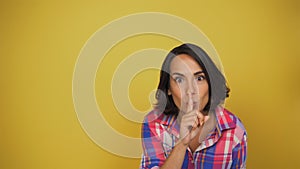 Brunette woman asks to be quieter. She puts her finger to her lips and smiles. Shooting in the studio on an isolated