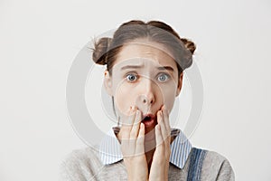 Brunette woman being deeply saddened by awful news covering open mouth with hands. Female person with hair in double