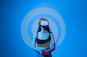 Brunette woman in a black t-shirt in VR headset looking up at the objects in virtual reality while playing a game or