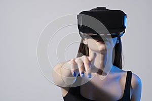 Brunette woman in a black t-shirt and VR headset looking up and trying to touch objects in virtual reality. VR is a