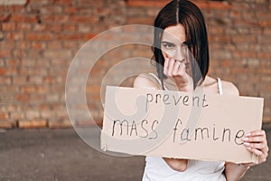 Brunette woman with cardboard hands to stop mass famine. Military actions of Russia against Ukraine