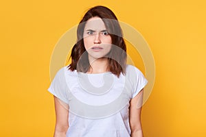 Brunette woman in casual clothes expressing disgust, dislikes something, having tensive look frowning face. Cauasian woman with photo