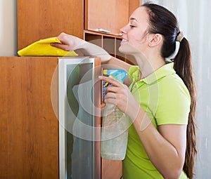 Brunette woman cleaning wooden furiture