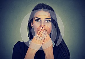Brunette woman covers her mouth with hands