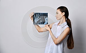 Brunette woman doctor or clinic patient holds hands X-ray good examination and looks at it satisfied