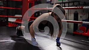 Brunette woman doing push ups on fists while training in boxing ring