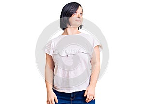 Brunette woman with down syndrome wearing casual white tshirt smiling looking to the side and staring away thinking