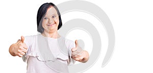 Brunette woman with down syndrome wearing casual white tshirt success sign doing positive gesture with hand, thumbs up smiling and