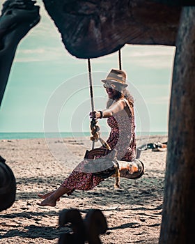 brunette woman enjoying swing on the beach