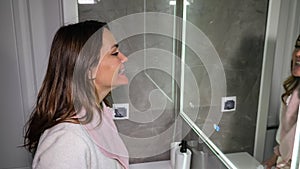 Brunette woman examines braces on teeth looking in mirror