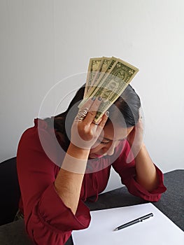 brunette woman with expression of despair and grabbing American dollar money