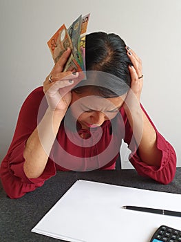brunette woman with expression of despair and grabbing Australian money