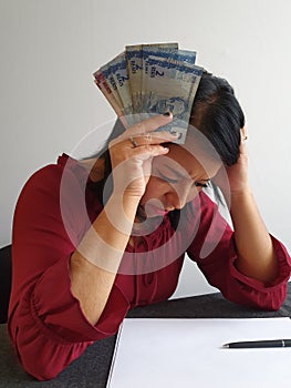 brunette woman with expression of despair and grabbing Brazilian money