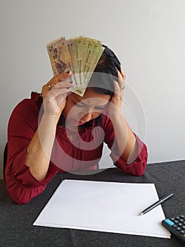 brunette woman with expression of despair and grabbing Chinese money