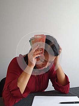 brunette woman with expression of despair and grabbing Costa Rican money